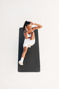 Portrait of young woman using mobile phone while standing against white background