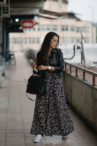 Attractive young lady with dress and leather jacket is posing.