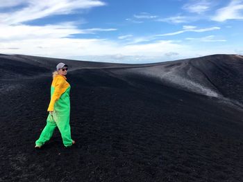 Woman in protective workwear walking on mountain against sky