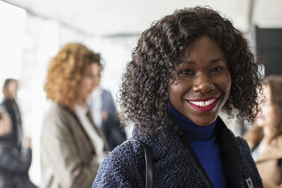 Portrait of happy businesswoman with curly black hair at conference center