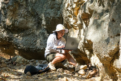 Side view of man sitting on rock