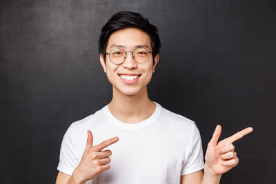 Portrait of smiling man standing against black background