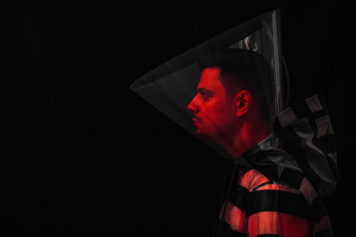 Profile view of man wearing protective collar against black background