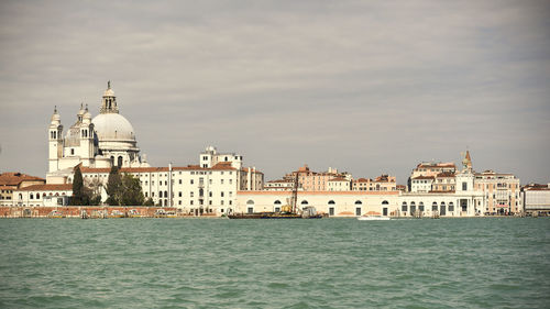 View of buildings at waterfront against cloudy sky