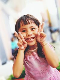 Portrait of smiling girl showing peace sign