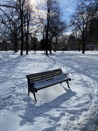 Empty bench in snow covered park