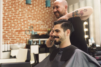 Barber cutting man hair in salon