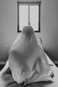 Rear view of woman with hand on bed at home