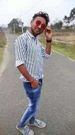 Portrait of young man wearing sunglasses standing on road