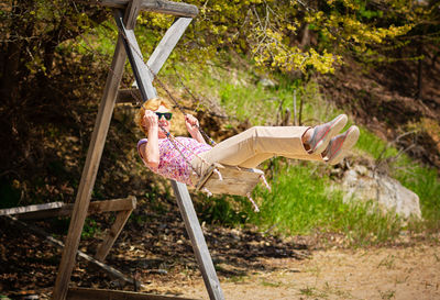 Senior woman joyfully swinging on a swing and having fan