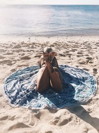 Rear view of woman lying on blanket at beach