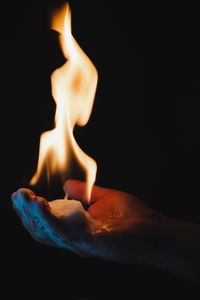 Close-up of burning candle against black background