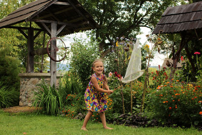 Happy 5-6 years old girl catching a butterfly in the village garden at summer