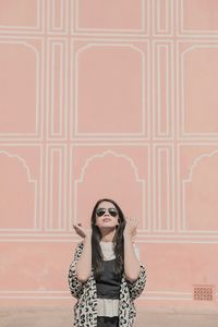 Portrait of woman standing against wall