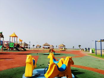 Playground in amusement park against clear blue sky