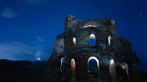 Low angle view of old building against blue sky at night