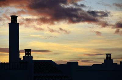 Silhouette of building against cloudy sky at sunset