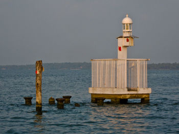 Lifeguard hut on wooden post in sea against sky