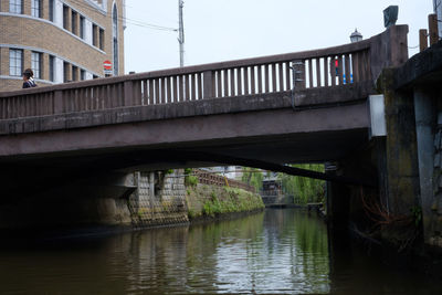 Bridge over river in city against sky