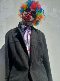 Young man in clown make up standing against wall