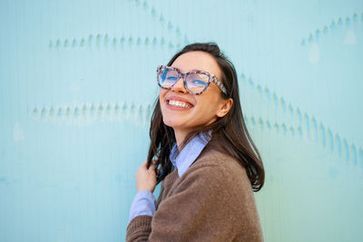 Young woman wearing sunglasses while standing against wall