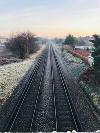 Railway tracks against clear sky during sunset