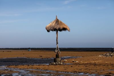 Traditional windmill on beach against sky