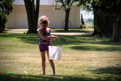 Full length of woman holding umbrella while standing on grass