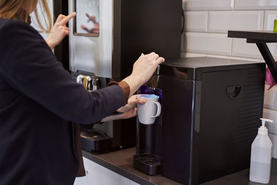 Woman preparing coffee in office kitchen