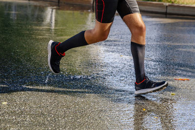 Legs male runner in compression socks running on wet asphalt