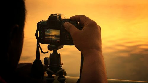 Close-up of man photographing against sunset