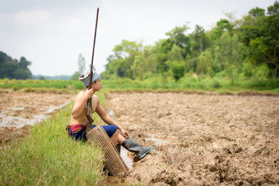 Full length of man sitting on field against sky