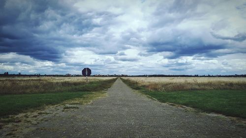 Road amidst field against sky