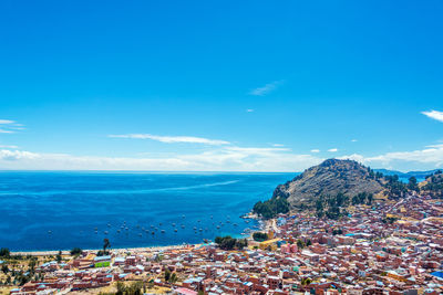 Buildings by sea against blue sky in town