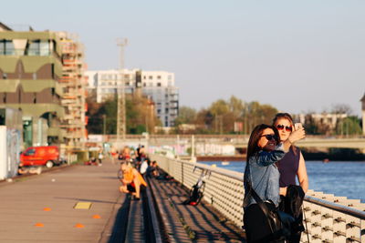 Portrait of friends in city against sky