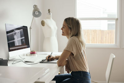 Side view of woman sitting on table at home