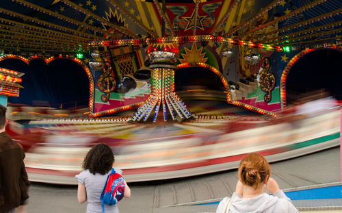 Rear view of women looking at blur carousel