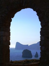 Scenic view of rock formations in sea seen through window