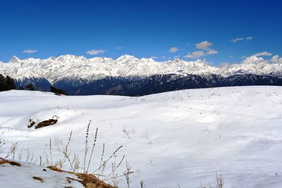 Scenic view of snow covered mountains against blue sky