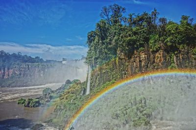 Scenic view of rainbow over landscape against sky