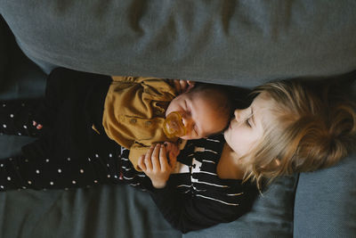 Sister with baby sibling on sofa