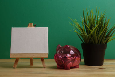 Close-up of coins in piggy bank with potted plant on table