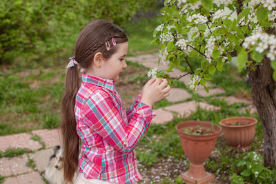 Side view of girl holding flowering plants