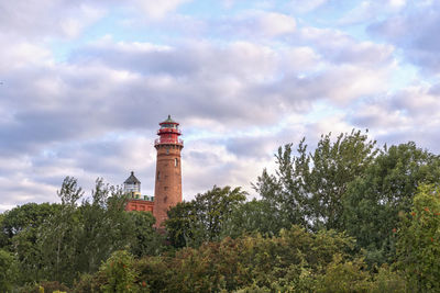 Low angle view of lighthouse by building against sky