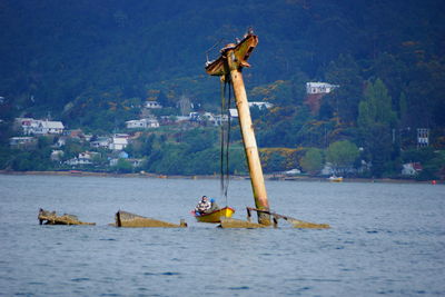 People in boat in front of shipwreck