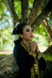 Girl with traditional clothing from java is hoping for something, the name of make up is yogya putri