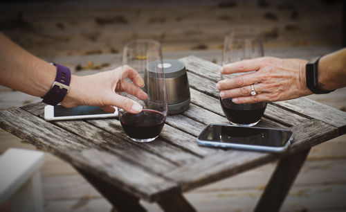 Cropped hands with drinks at table