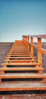 Staircase leading towards sea against clear blue sky