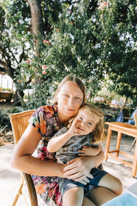 Portrait of smiling girl sitting with grandmother outdoors