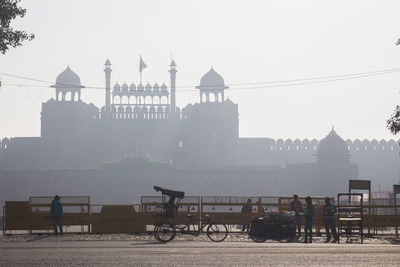 People on street against red fort in foggy weather